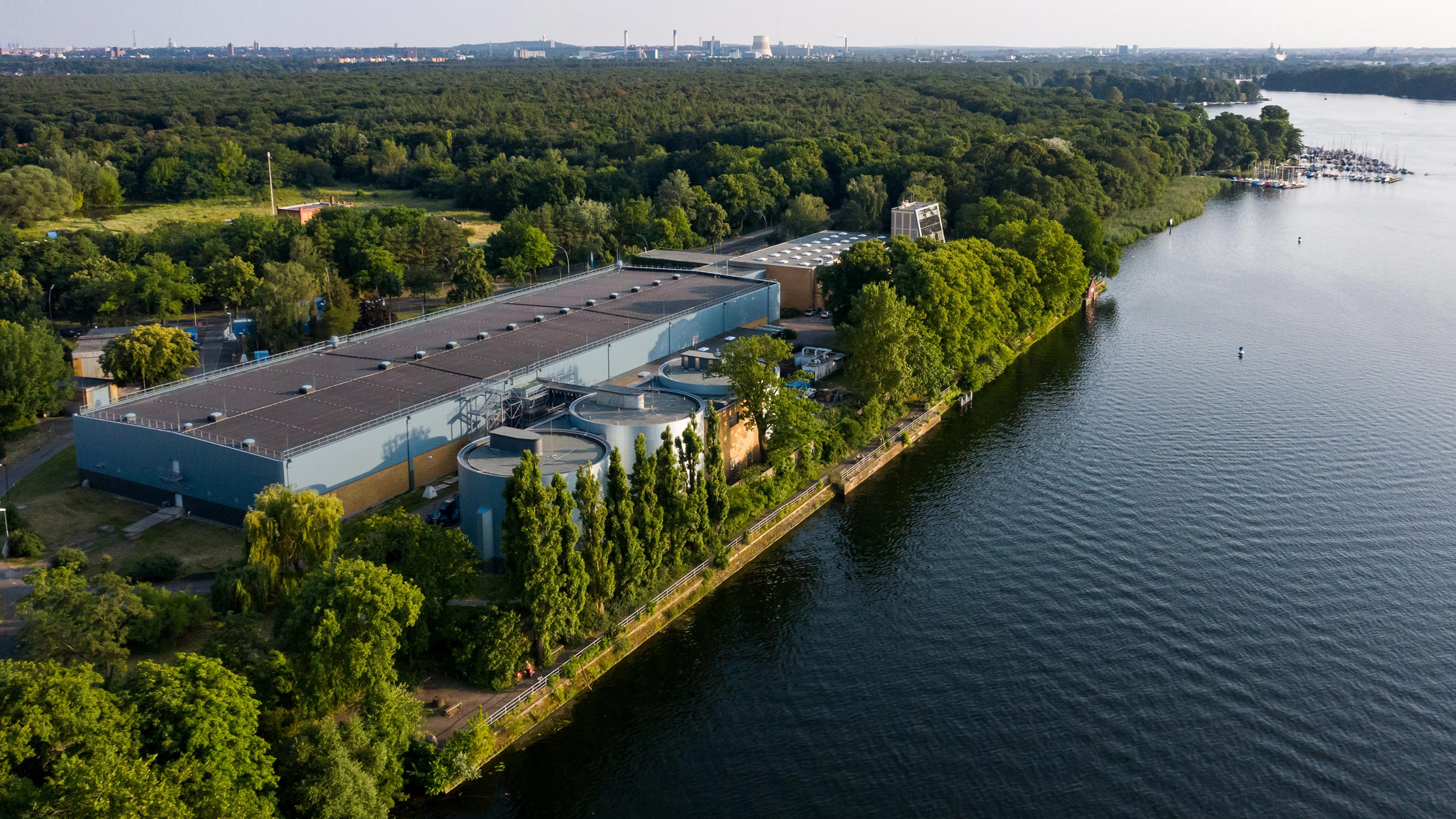 Luftbild von einem Fabrikgebäude mit großen Tanks, das an einem Gewässer steht
