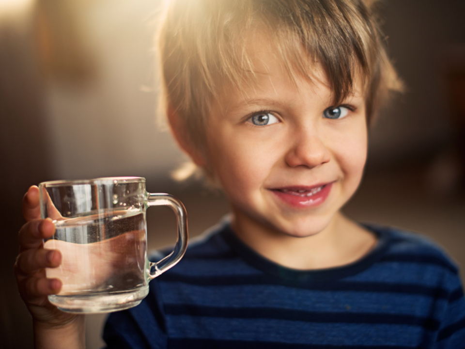 Junge hält ein Glas Wasser in der Hand 